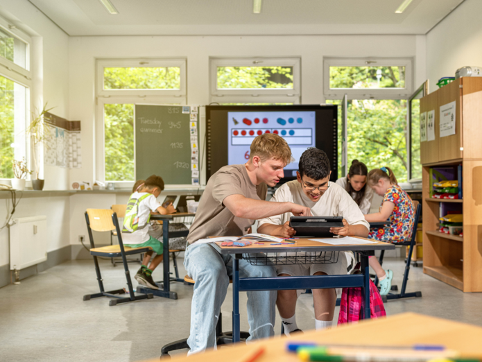 Ein FSJ-Ableistender erklärt einem Schüler etwas am Tablet