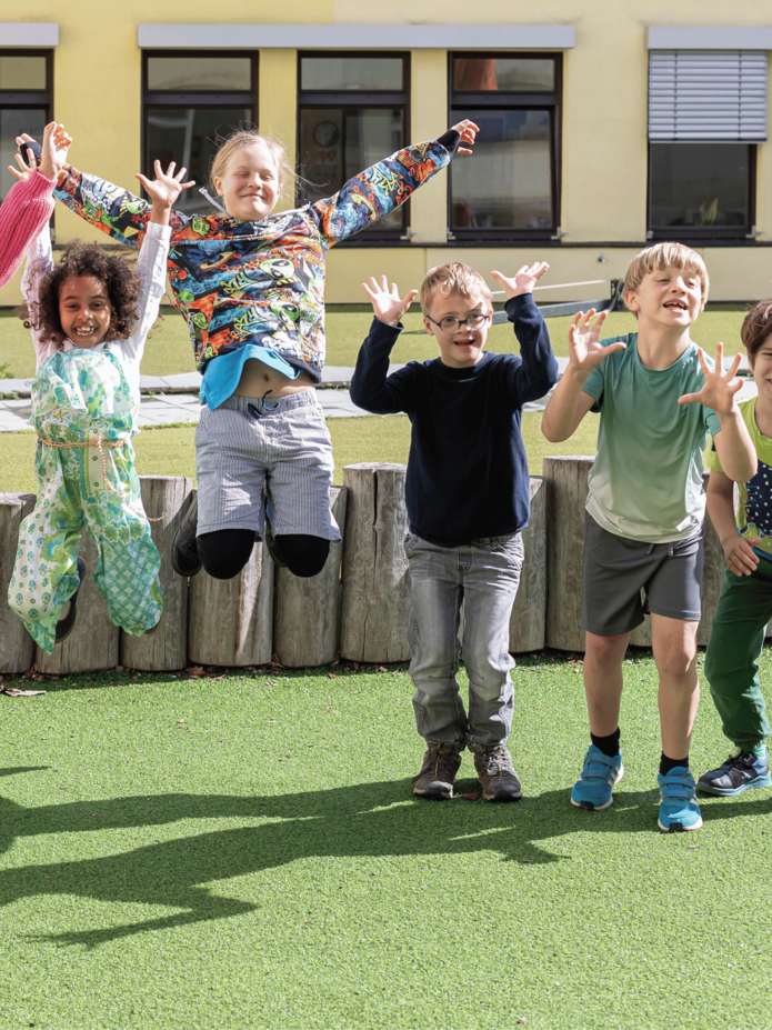 Fünf Grundschüler im Pausenhof der Torwiesenschule springen in die Luft