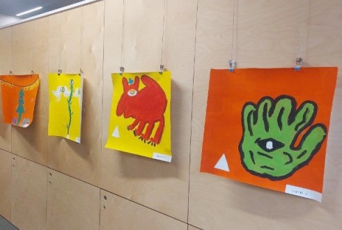 Ein Teil der Kunstwerke, die während der Thementage entstanden sind, hängen nebeneinander an einer Wand.