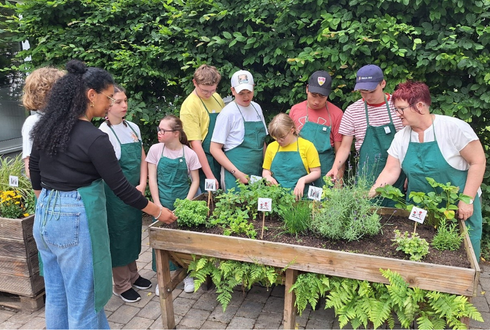 Schüler und Schülerinnen der Berufsschulstufe zwei des SBBZ bepflanzen ein Hochbeet mit Kräutern